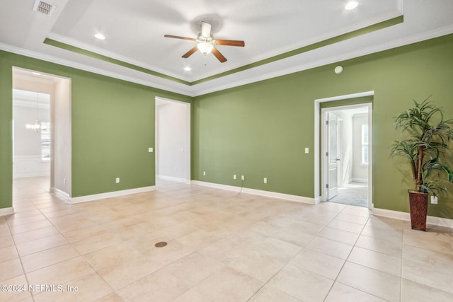 unfurnished room with a tray ceiling, ceiling fan with notable chandelier, and ornamental molding