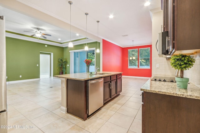 kitchen featuring appliances with stainless steel finishes, a center island with sink, light stone counters, and hanging light fixtures