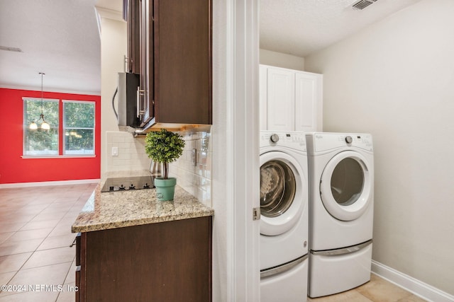 washroom with cabinets, a notable chandelier, a textured ceiling, light tile patterned floors, and washer and dryer