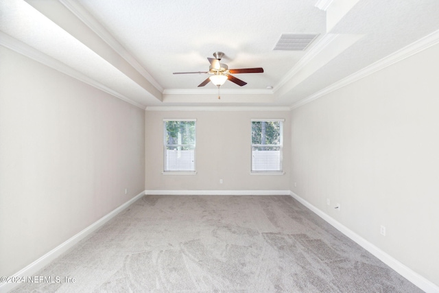 carpeted empty room featuring ceiling fan, a raised ceiling, and ornamental molding