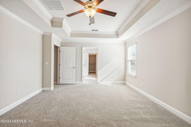 spare room with carpet, ornamental molding, a textured ceiling, a tray ceiling, and ceiling fan