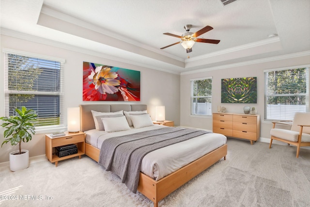 carpeted bedroom featuring a tray ceiling, ceiling fan, and crown molding