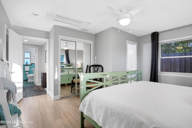 bedroom with ceiling fan, multiple windows, light hardwood / wood-style flooring, and a closet