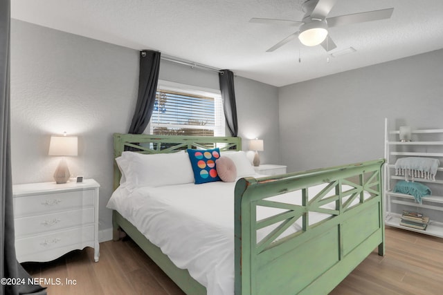 bedroom featuring ceiling fan, hardwood / wood-style floors, and a textured ceiling