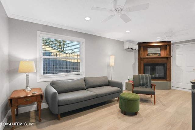 living room featuring ceiling fan, a large fireplace, an AC wall unit, crown molding, and light wood-type flooring