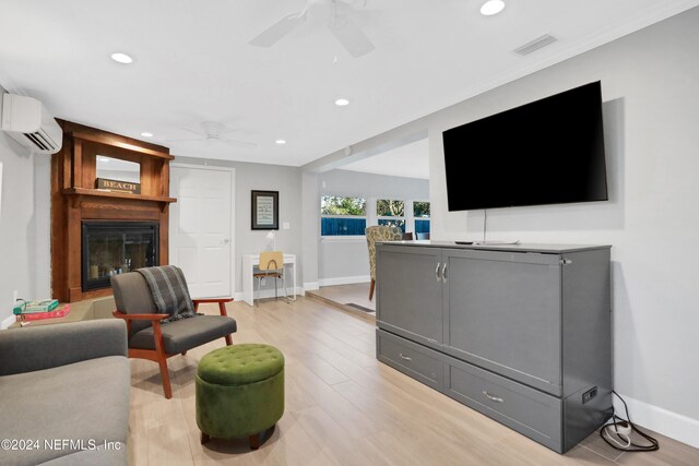 living room with a wall mounted air conditioner and light hardwood / wood-style flooring