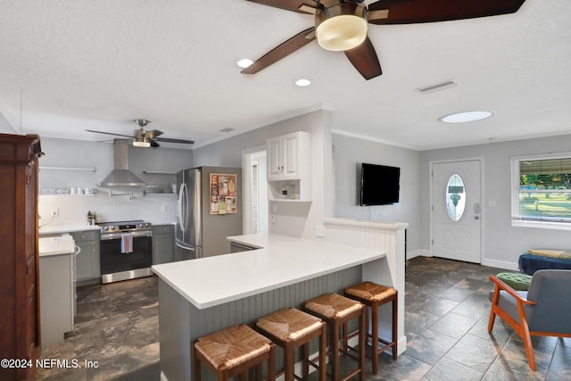 kitchen featuring wall chimney exhaust hood, stainless steel appliances, kitchen peninsula, a breakfast bar, and white cabinets