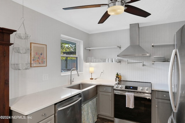 kitchen featuring wall chimney range hood, crown molding, sink, gray cabinets, and appliances with stainless steel finishes