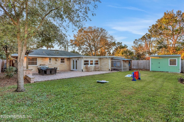 rear view of property featuring a lawn, a patio area, and a shed