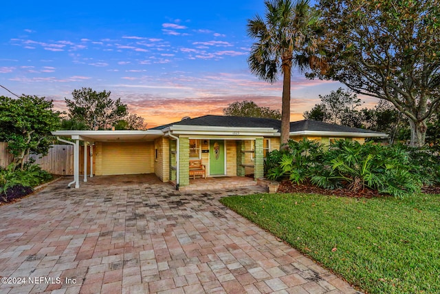 ranch-style home with a carport and a yard