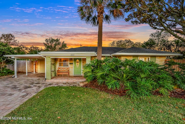 view of front of property featuring a carport and a lawn