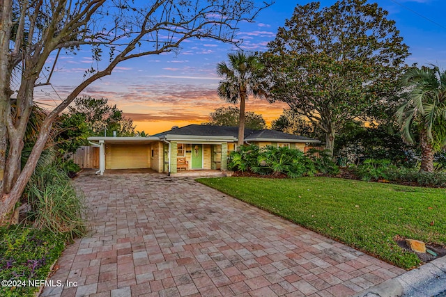 ranch-style house featuring a carport and a yard