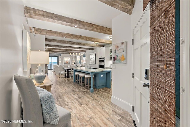 interior space featuring sink, light wood-type flooring, and beam ceiling