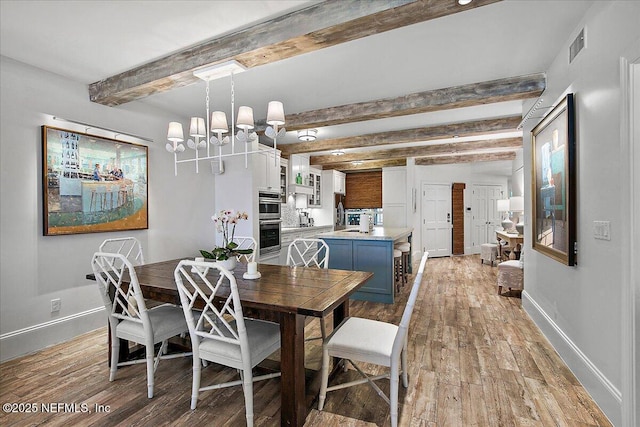 dining room with a chandelier, beamed ceiling, and light hardwood / wood-style flooring