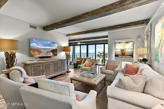 living room with hardwood / wood-style floors, ceiling fan, beamed ceiling, and expansive windows