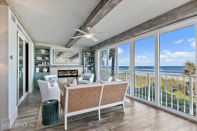 living room with a view of the beach, a high end fireplace, a water view, hardwood / wood-style flooring, and beam ceiling