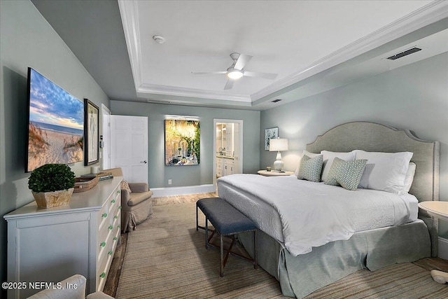 bedroom featuring ensuite bath, ceiling fan, a tray ceiling, and crown molding