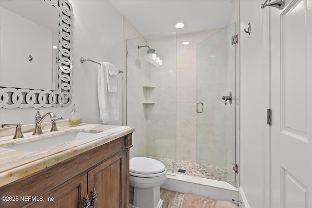 bathroom with toilet, an enclosed shower, hardwood / wood-style floors, and vanity