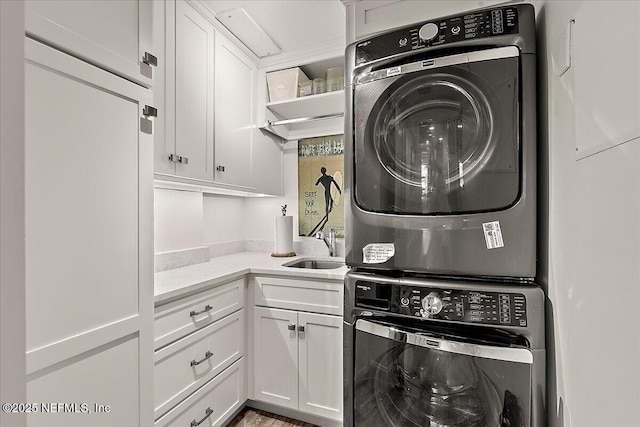 washroom featuring cabinets, stacked washer / dryer, and sink