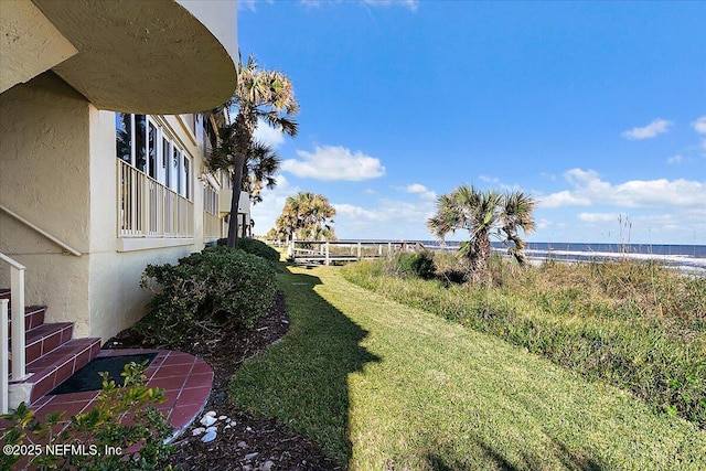 view of yard with a water view and a view of the beach