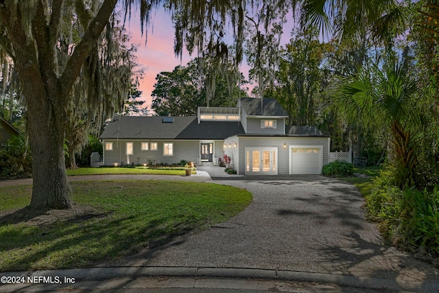 view of front facade with french doors, a garage, and a lawn