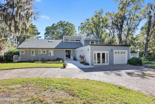 view of property featuring french doors, a garage, and a front lawn