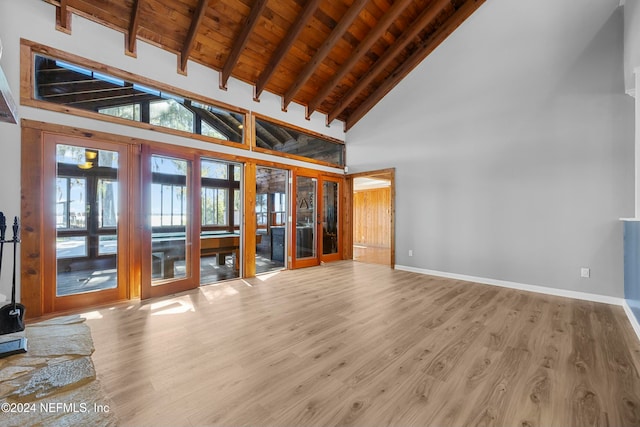 unfurnished living room with hardwood / wood-style floors, high vaulted ceiling, and french doors