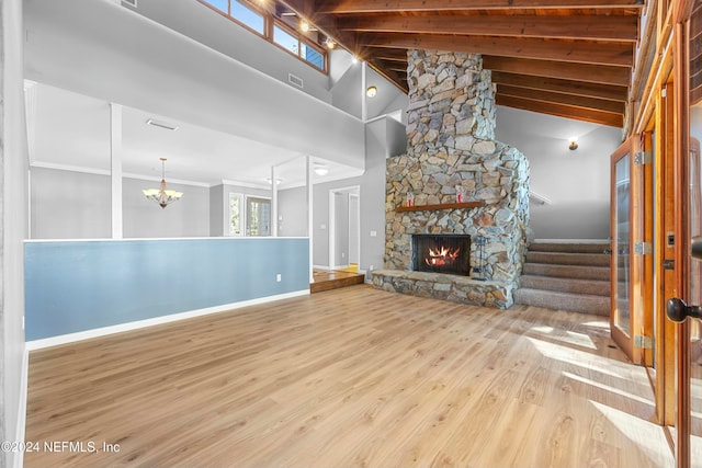 unfurnished living room with an inviting chandelier, high vaulted ceiling, crown molding, light hardwood / wood-style floors, and a fireplace