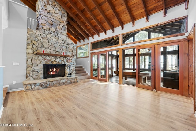 unfurnished living room with a healthy amount of sunlight, wooden ceiling, high vaulted ceiling, and french doors