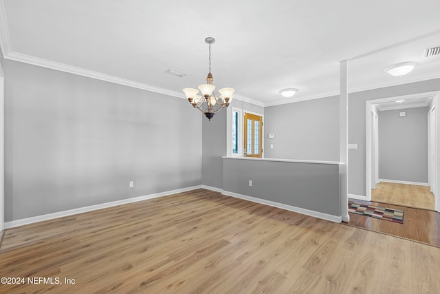 spare room with light hardwood / wood-style floors, an inviting chandelier, and ornamental molding