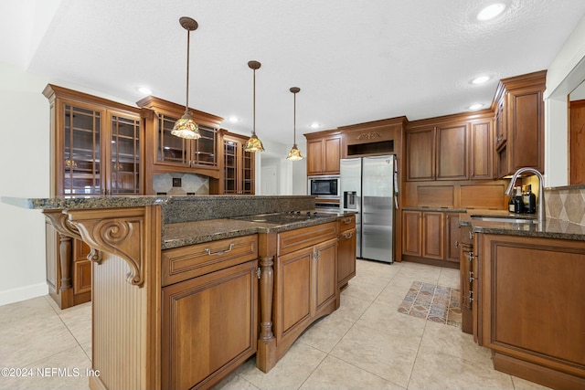 kitchen featuring sink, hanging light fixtures, dark stone counters, a breakfast bar area, and black appliances