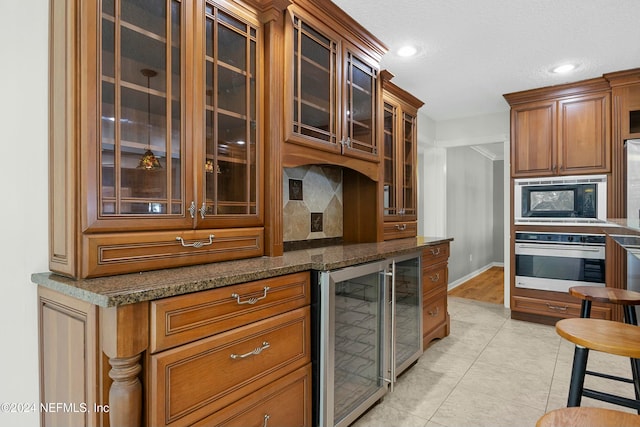 kitchen with dark stone countertops, decorative backsplash, oven, and beverage cooler