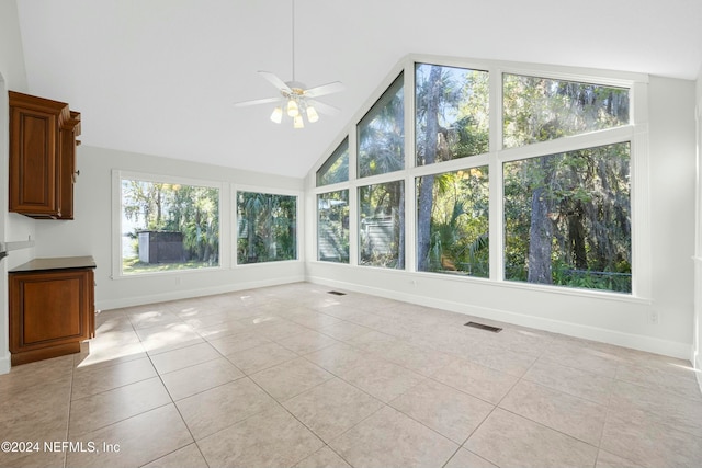 unfurnished sunroom featuring ceiling fan, a healthy amount of sunlight, and vaulted ceiling