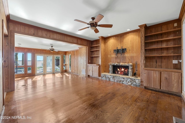 unfurnished living room featuring wooden walls, french doors, hardwood / wood-style floors, and ornamental molding