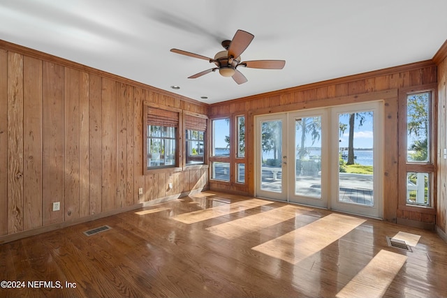 spare room featuring hardwood / wood-style floors, ceiling fan, wooden walls, and french doors