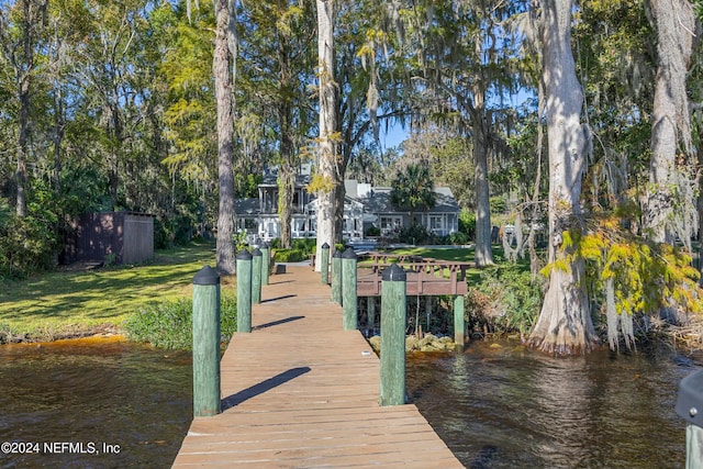 view of dock with a yard and a water view