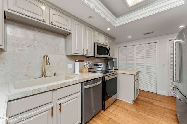 kitchen with light wood-type flooring, tasteful backsplash, ornamental molding, stainless steel appliances, and sink