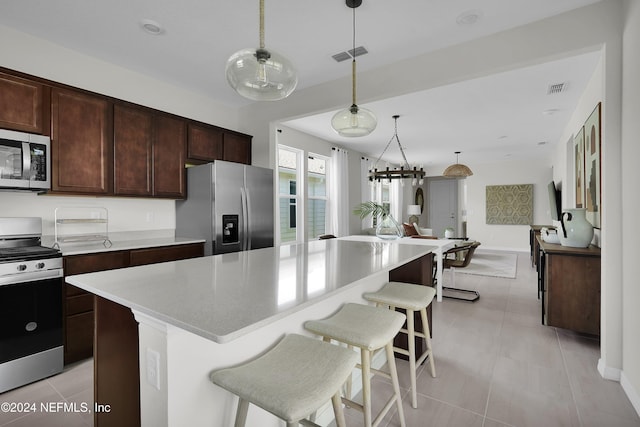 kitchen with decorative light fixtures, dark brown cabinetry, stainless steel appliances, and a kitchen island