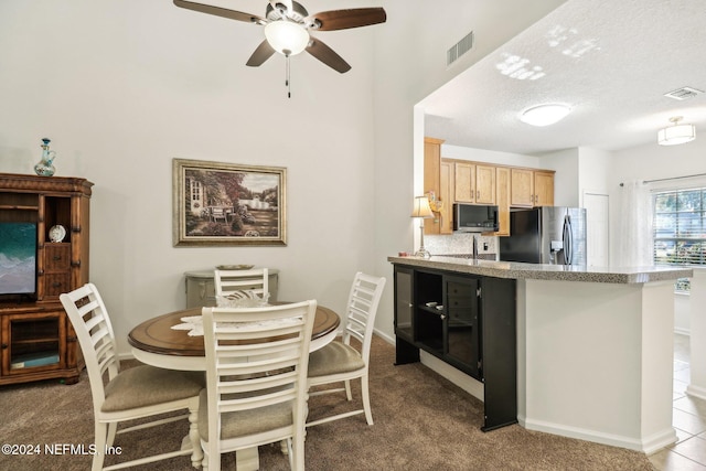 kitchen featuring light carpet, light brown cabinets, stainless steel appliances, and a textured ceiling