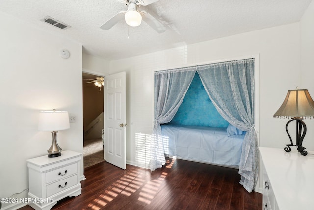 bedroom featuring ceiling fan, dark hardwood / wood-style floors, and a textured ceiling