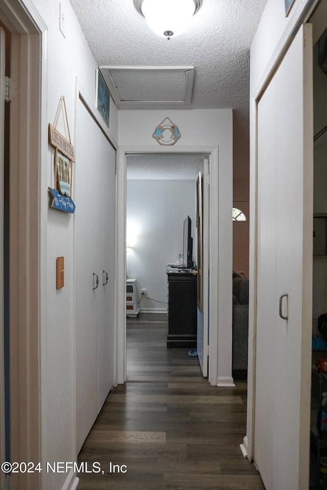 hall with dark hardwood / wood-style flooring and a textured ceiling