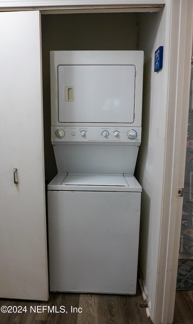 clothes washing area featuring dark hardwood / wood-style flooring and stacked washer / drying machine