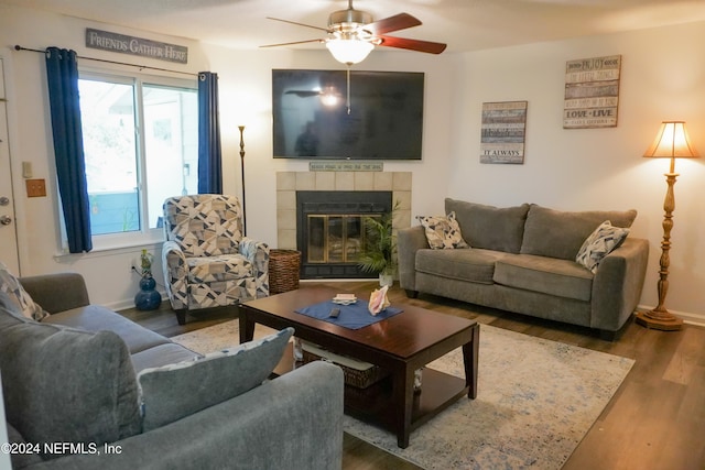 living room with hardwood / wood-style floors, ceiling fan, and a tiled fireplace