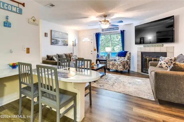 dining area featuring ceiling fan, dark hardwood / wood-style floors, and a tiled fireplace