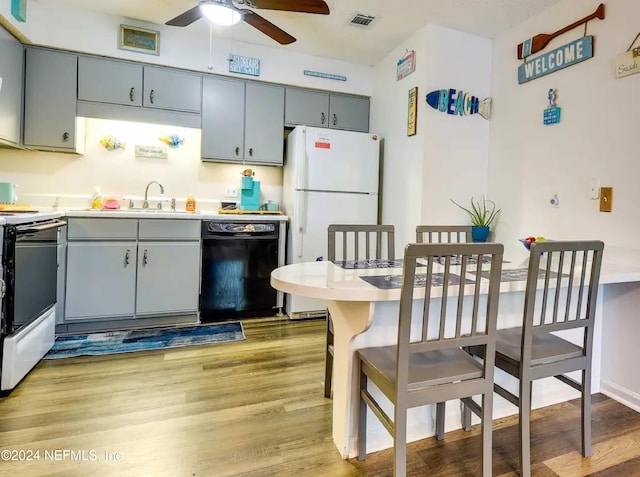 kitchen with stove, light wood-type flooring, ceiling fan, sink, and black dishwasher