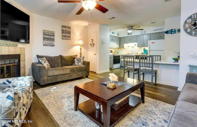 living room with a tiled fireplace, sink, and hardwood / wood-style flooring