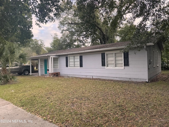 ranch-style house featuring a front lawn and a carport