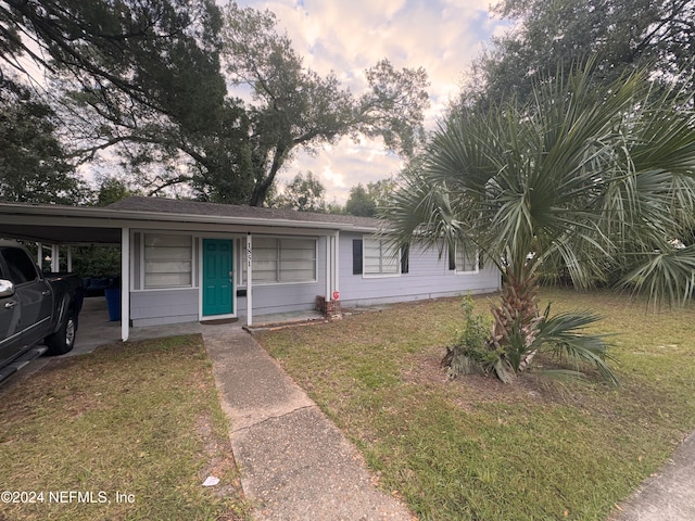 view of front of home with a carport and a lawn