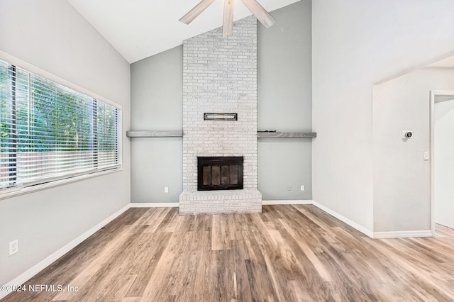 unfurnished living room with high vaulted ceiling, hardwood / wood-style flooring, a brick fireplace, and ceiling fan