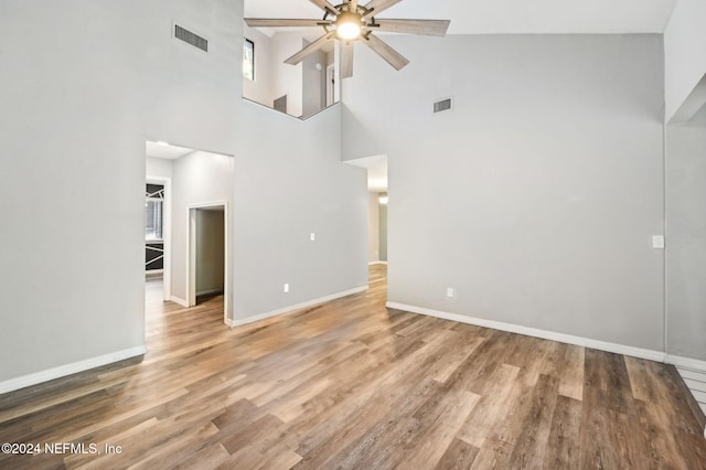 unfurnished living room featuring wood-type flooring, high vaulted ceiling, and ceiling fan